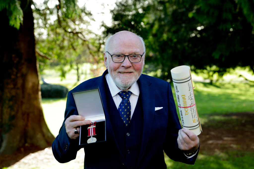 Michael Downes holding up his silver medal and parchment at the Oireachtas National Bravery awards